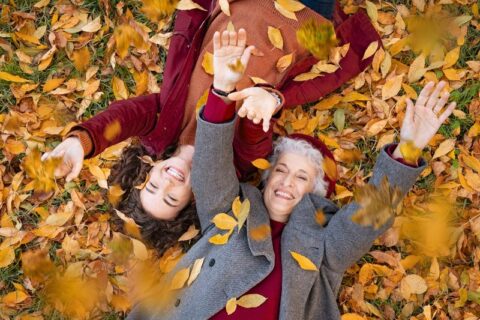 Grandmother and Granddaughter laying on fall leaves in Utah County