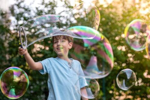 Boy playing with bubbles outside