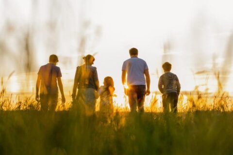 Family walking through a field in the sunset