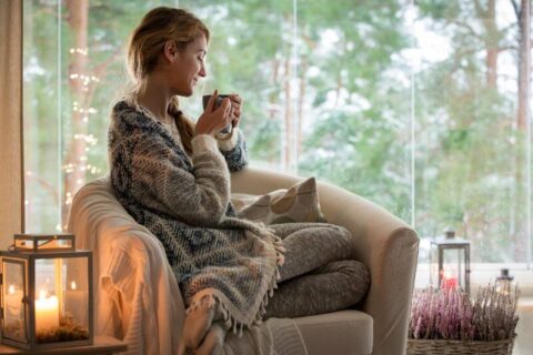 Girl drinking coffee in warm living room near window