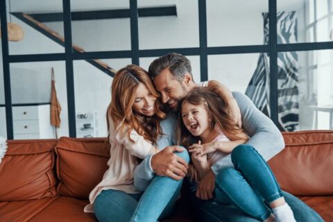 Father and mother playing with daughter in living room