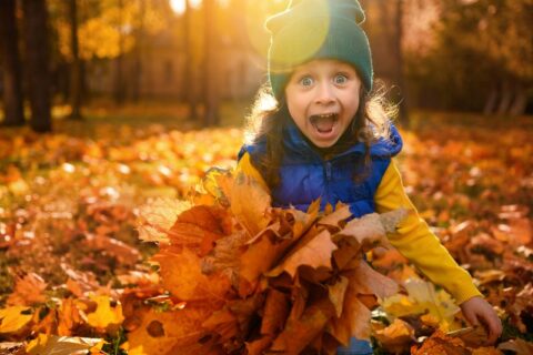 Girl playing in fall leaves