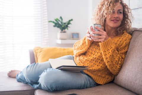 Woman reading on the couch and drinking coffee