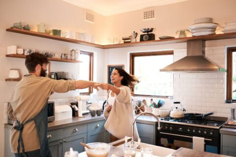 Young happy couple dancing in the kitchen while preparing breakfast at home